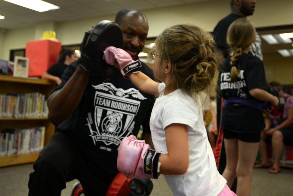 тренер по боксу тренирует молодого ребенка